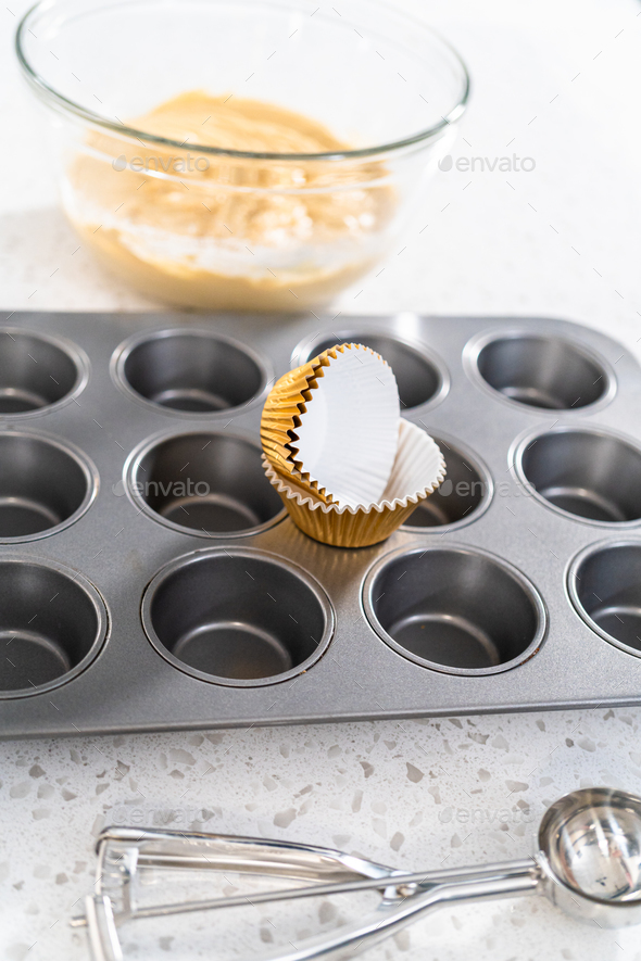 Scooping cupcake batter with a dough scoop into cupcake foil