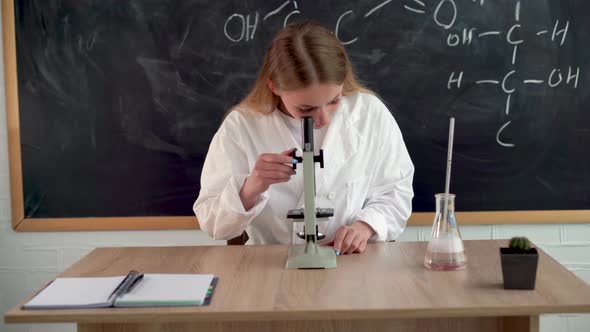 A Serious Girl Chemist Conducts Research in a College Classroom for Students Looking Through a alt