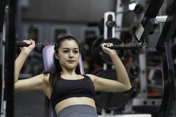 Beautiful fit woman trains in the gym, fitness. woman flexing muscles on chest press gym machine, Co