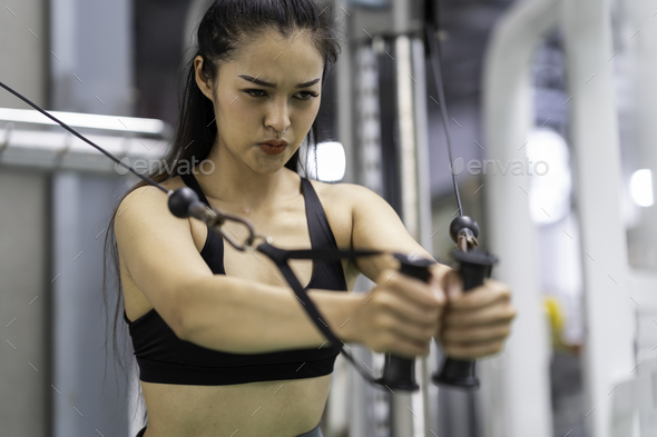 Young Asia lady exercise doing exercise-machine Cable Crossover fat burning workout in fitness class