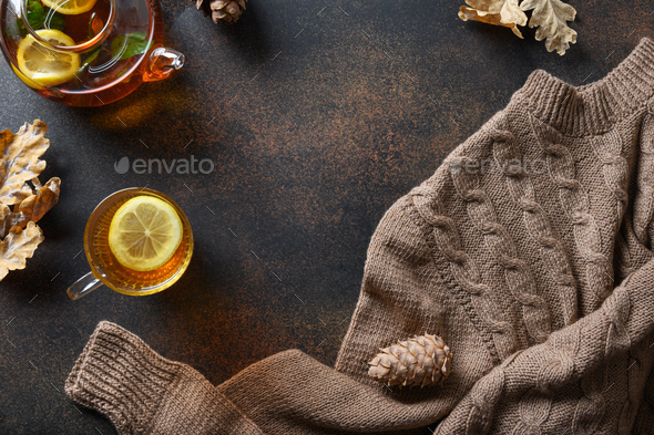 Fall cozy composition with warming tea, fall leaves and sweater. View from above.