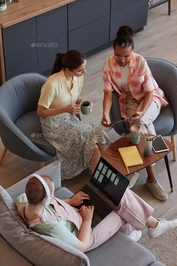 Three young women using laptop in meeting while working on IT project