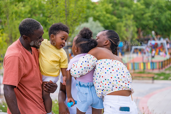 African black ethnic family with children in playground, hugging after school and kissing