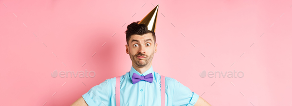 Holidays and celebration concept. Close-up of confused male entertainer in party hat and bow-tie
