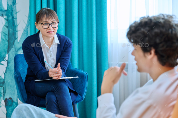 Female psychologist talking to young male, individual therapy session