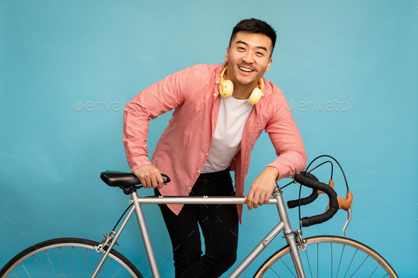 Young man posing next to his bicycle and smiling Stock Photo | Adobe Stock