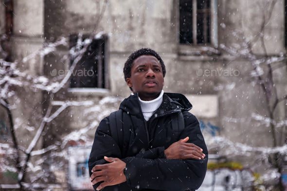Pensive african american guy arms crossed in snowy russian winter