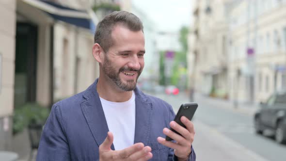 Mature Adult Man Celebrating on Smartphone alt