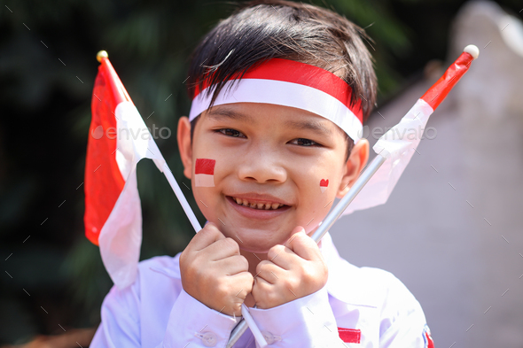 Adorable young boy with Indonesian flag face painting looking at camera ...