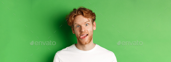 Emotions and fashion concept. Close up of funny redhead man showing silly faces, sticking tongue