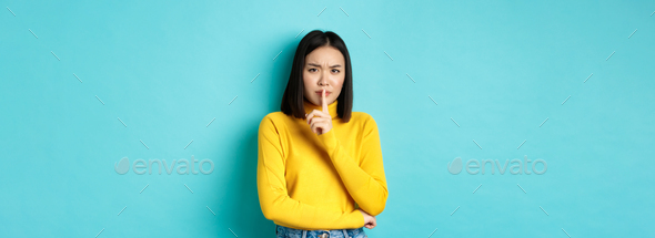 Disappointed asian woman telling to be quiet, scolding loud person with hush gesture, shushing at