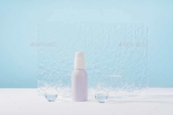 Cosmetic cream metallic pump bottle mockup on blue background with stylish props, glass balls and