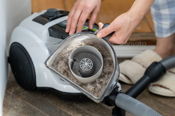 Woman opening dust filter out of vacuum cleaner. Housework, household chores