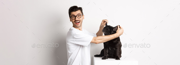 Happy young man looking at camera, showing cute dog ears and feeling rejoice, adopting a pet