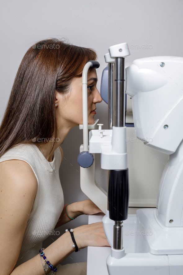 Female patient undergoing an eye examination using a specialized diagnostic device.