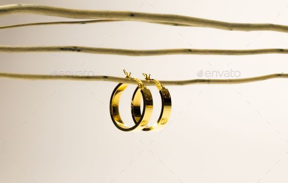 Golden hoop earrings hanging from a wire on the white background