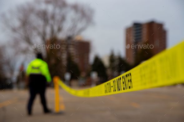a police officer walking through a parking lot with a yellow tape