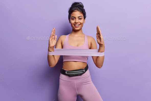 Athletic woman in sportswear showcases strength as she stretches rubber resistance band her radiant