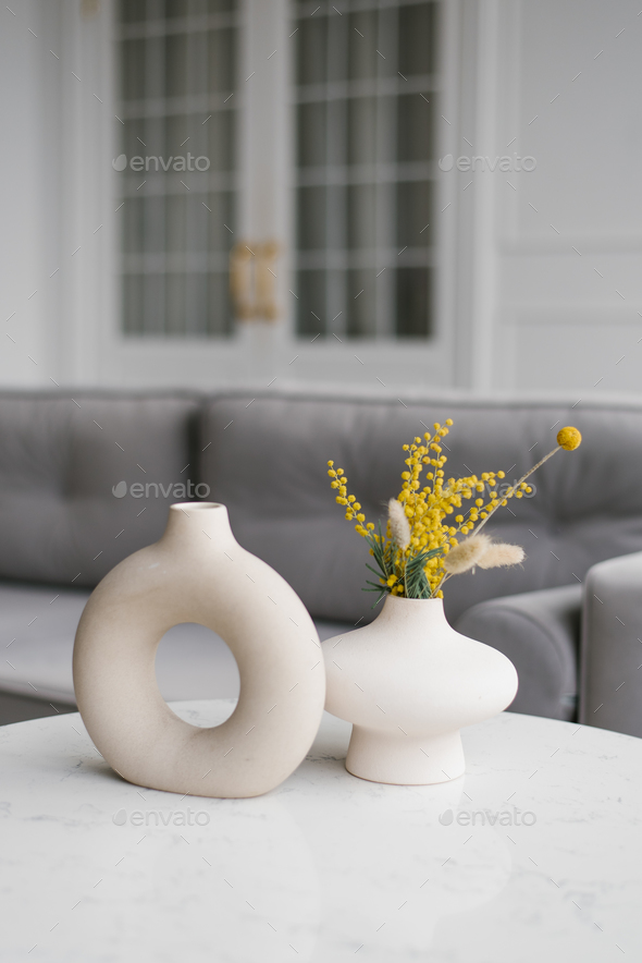 Two decorative ceramic modern round mimosa vases with a hole inside on the table in the living room