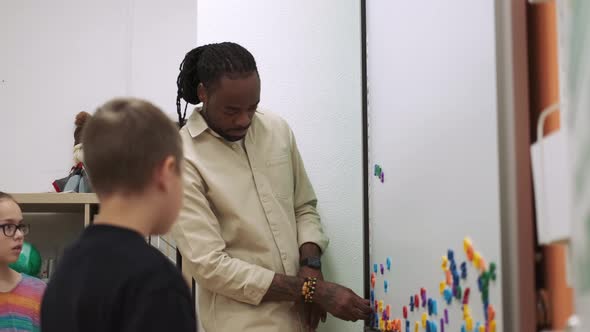 An African American Teacher Teaches a Child Using a Magnetic Board in the Classroom alt
