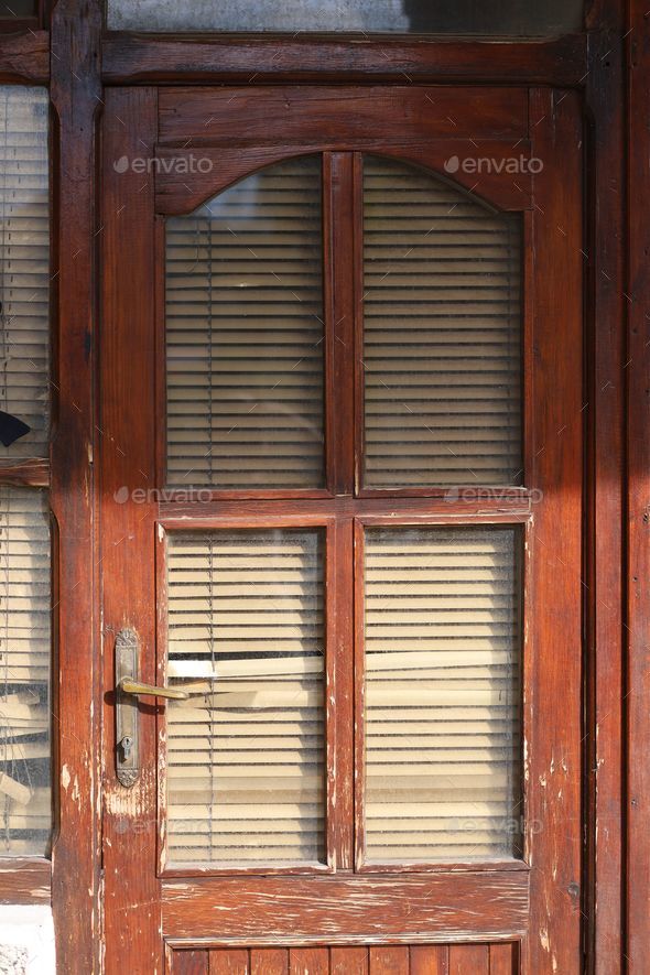 Outdoor shot of a traditional wooden door with vertical blinds in the background