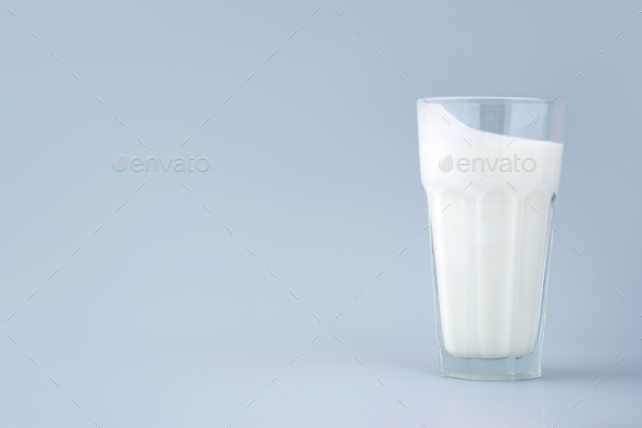 Probiotic drink, buttermilk or yogurt. Kefir in a tall faceted glass on minimalistic blue background
