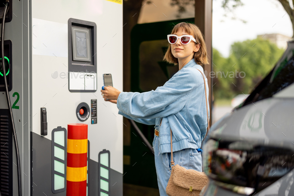 Woman going to charge electric car on public power station