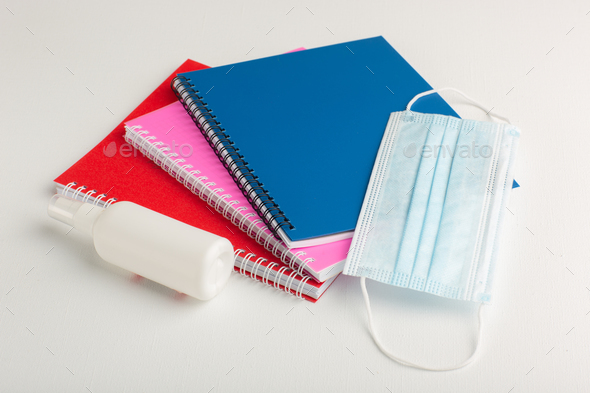 front view colorful copybooks with spray and mask on white background school notepad pencil color