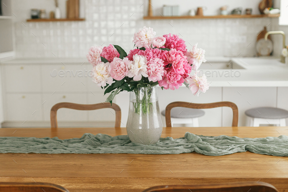 Vases with Beautiful Flowers on Table in Kitchen Interior. Stock