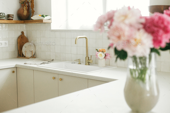 Modern kitchen design. Stylish brass faucet and white granite sink, kitchen cabinets