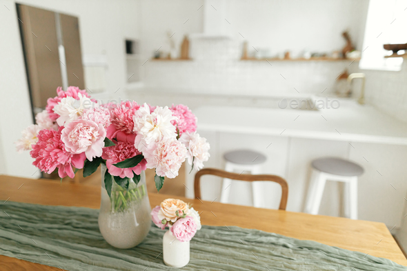Vases with Beautiful Flowers on Table in Kitchen Interior. Stock