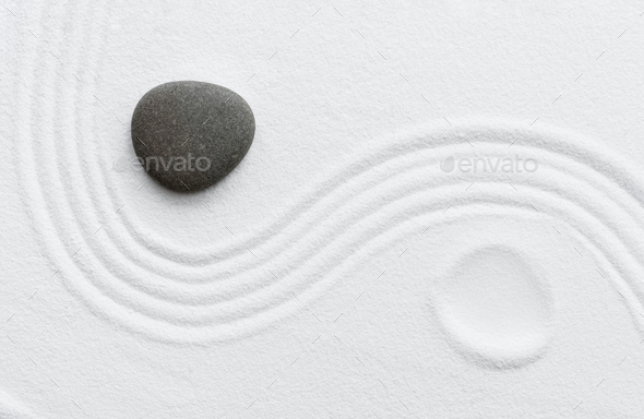 Zen Stone in Japanese garden with grey rock sea stone on white sand texture, Yin and Yang symbol