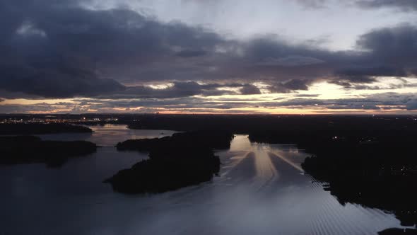 Finnish nature. Drone view above islands, rivers and lakes with city light on the background. Pedest alt