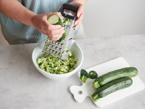 woman grating zucchini with a stainless steel hand grater Stock