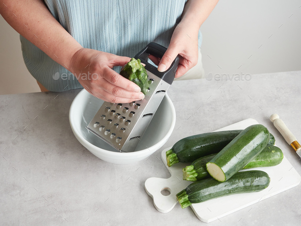 woman grating zucchini with a stainless steel hand grater Stock
