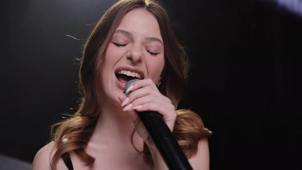 Singing Woman with Microphone on Music Concert Over Black Background