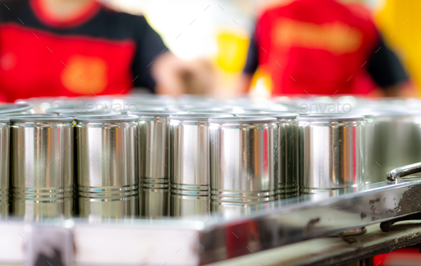 Many cans on blur workers. Canned fish factory. Food industry. Workers working in canned food factor
