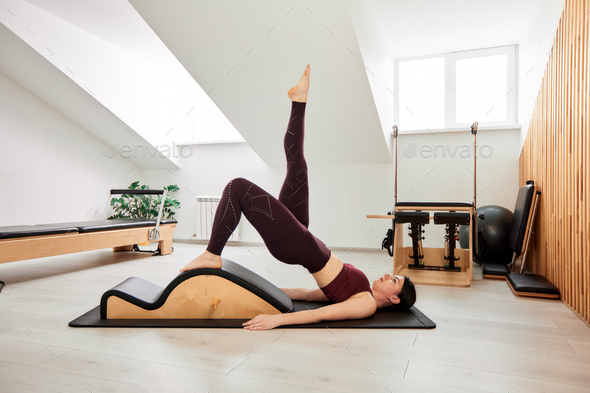 Girl doing pilates exercises with reformer bed in studio Stock