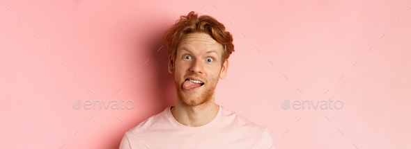 Headshot of funny redhead guy showing tongue, making silly faces at ...