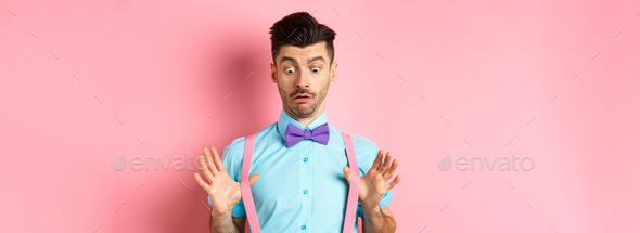 Funny guy with moustache and bow-tie, adjusting his suspenders and looking down with confused and