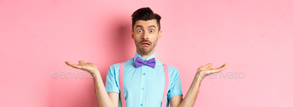 Portrait of confused male model in bow-tie and funny shirt, shrugging and looking clueless, know