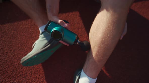 An Athlete Massages with a Percussion Therapy Gun to Relieve the Pain of Muscle Aches After a alt