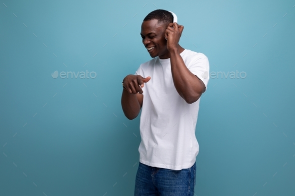 well-groomed handsome young african guy dancing to music in headphones
