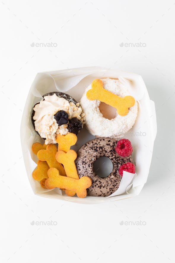 Of a selection of doughnuts in a cardboard box, decorated with dog snacks