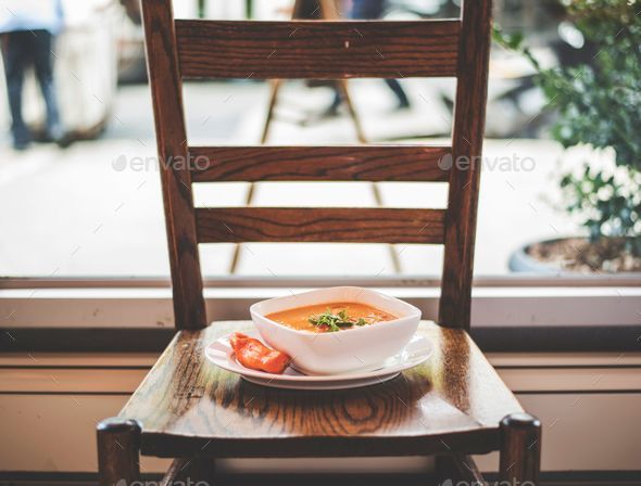 Ceramic bowl filled with a steaming vegetable soup on a wooden chair