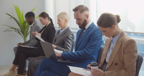 Group of Diverse Business People with Documents and Gadgets Sitting in Row alt