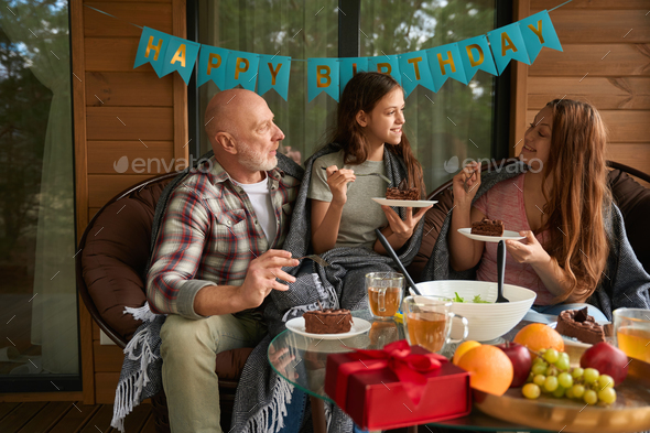 Family of three enjoying birthday party on cottage veranda