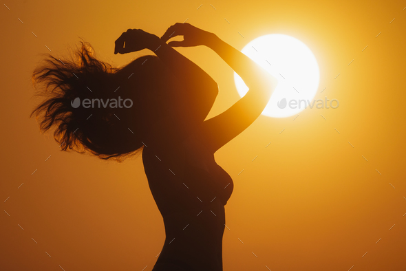 Profile of Young Bikini Beach Woman Silhouetted Against a Big Golden Sun Disk