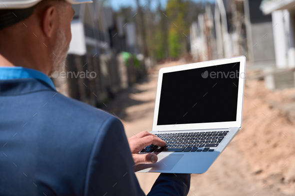 General contractor checking information about construction site on laptop