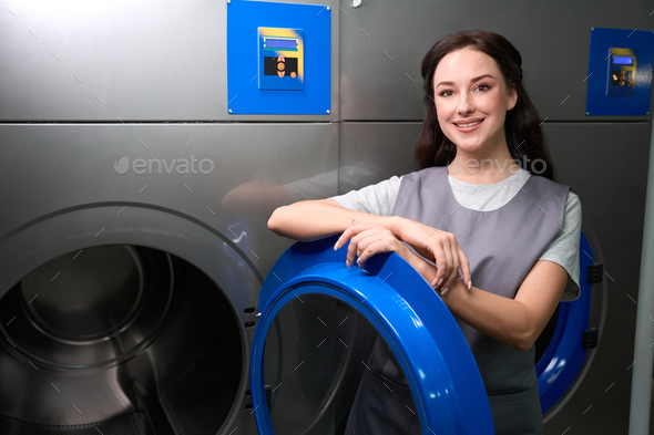 Woman standing near professional washing or drying machine